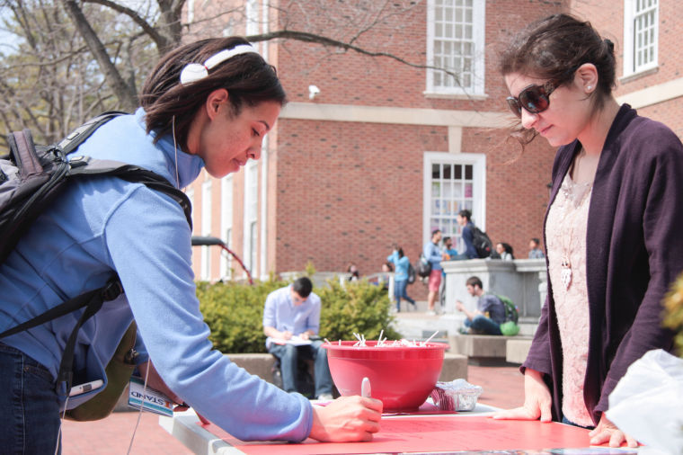 Alexis Byrd, senior in ACES, signs the Bystanders Pledge for Sexual Assault Awareness Month as Yarah Kudaimi, senior in LAS, observes on the Main Quad on March 31, 2014.