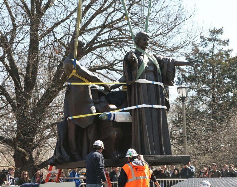 Workers struggle for almost an hour before finally placing the Alma Mater back onto her stand on the corner of Wright and Green on Wednesday, April 9th, right before noon.