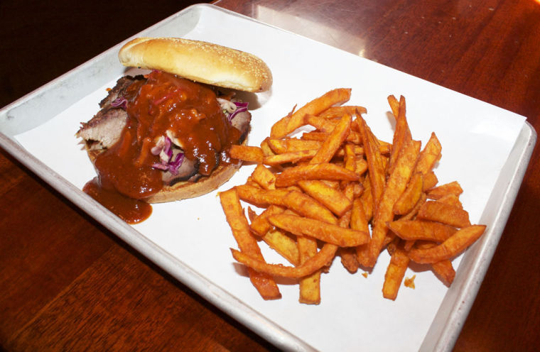 Pictured is a beef brisket sandwich covered in Georgia peach barbecue sauce and a side of sweet potato fries, served at the Black Dog Smoke and Ale House in Urbana. This barbeque joint is well-known by students and community members alike for its mouth-watering food. 
 