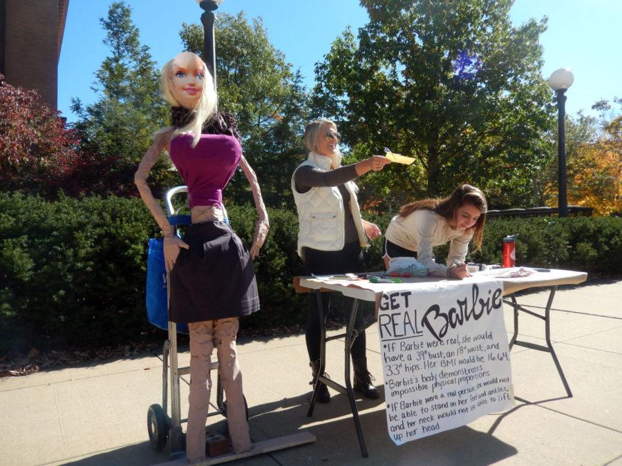 Students Georgia Christus and Chloe Peterson work next to a human-size Barbie on the Engineering Quad on Monday.