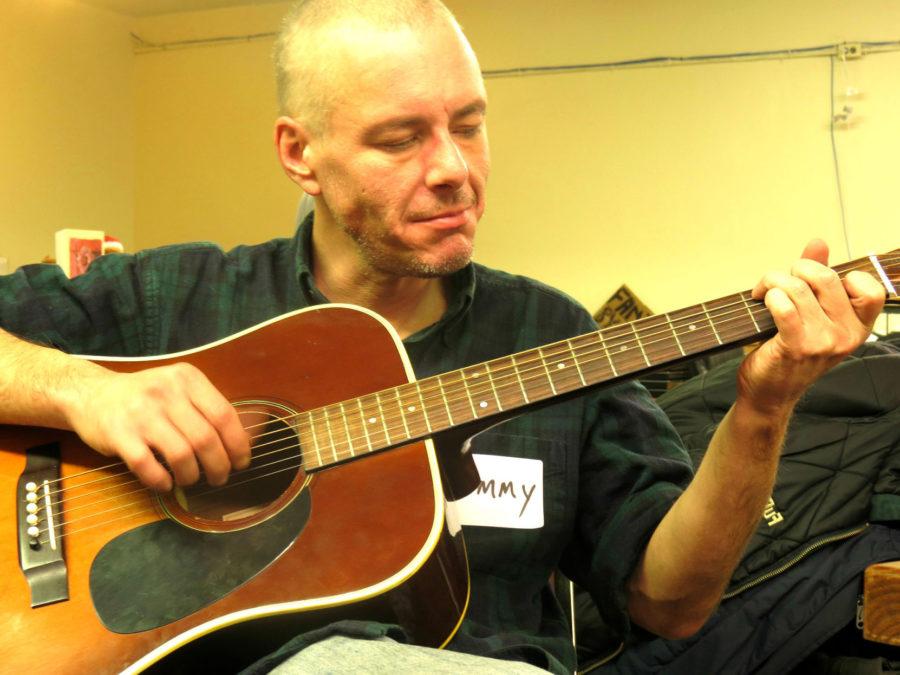 Tommy, a guest at The Phoenix, strums his guitar in the recreation room of the drop-in center on Dec. 16.