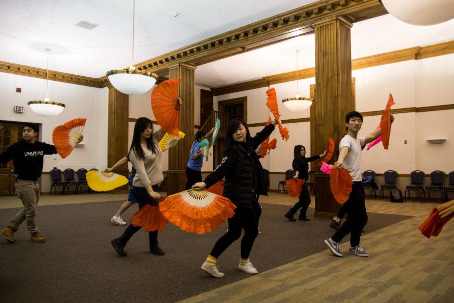 Sam Fu (right) leads Chinese fan choreography during practice for the Asian American Association’s 29th annual fashion show. The show will be at Foellinger Auditorium on Saturday. 