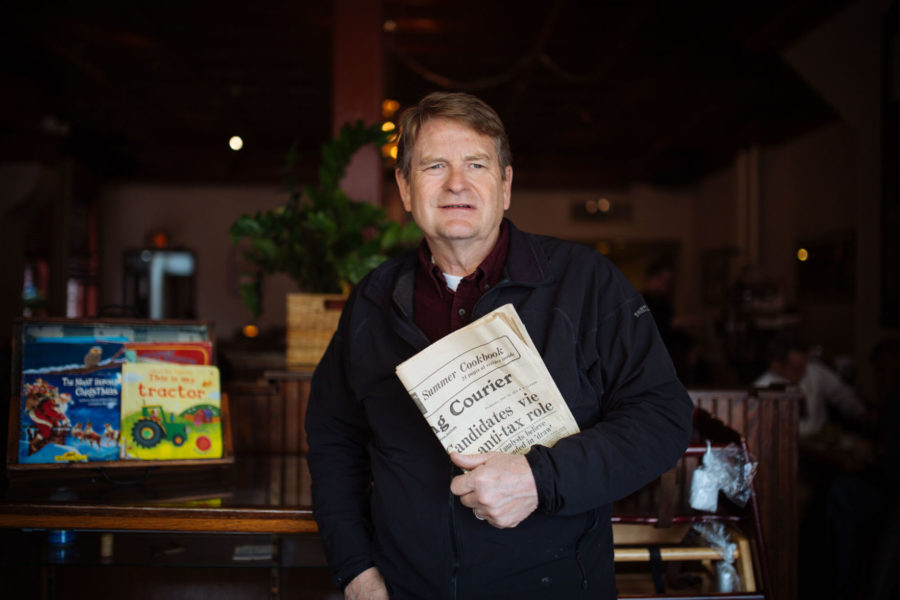 Allen Strong, the owner of The Courier Cafe, is holding the old newspapers in the cafe at March 20.