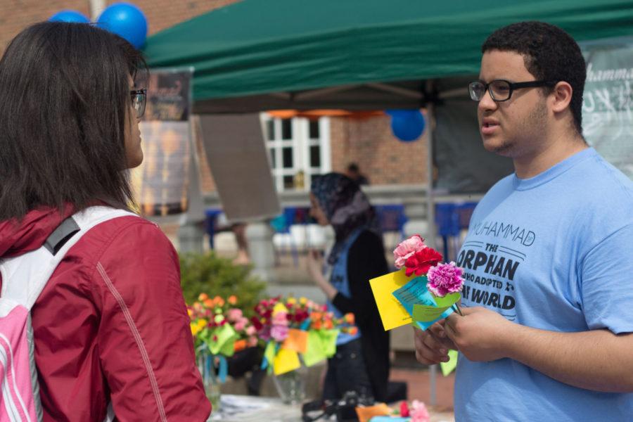 Aly Taha, sophomore in Business, gives a flower to Kayla Smith, senior in LAS, as he explains the significance of Muhammad during the “Muhammad: The Orphan Who Adopted the World” event on the Main Quad on Wednesday.