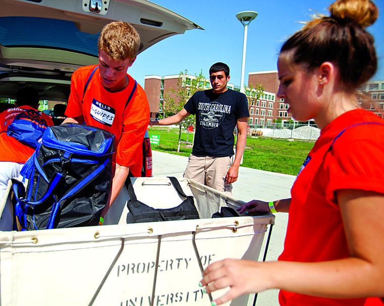 An I-Guide loads a duffle bag out of a freshmans van moving into Hopkins Hall during move-in week.