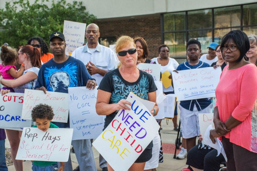 Champaign-Urbana residents hold a prayer vigil to protest Gov. Bruce Rauners proposed budget cuts to child care, home health care and Medicaid outside the Unemployment Office in Champaign on Tuesday, June 30.