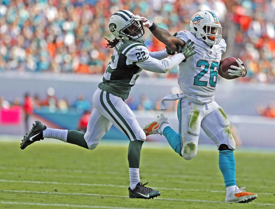 Miami Dolphins running back Lamar Miller (26) stiff arms New York Jets cornerback Marcus Williams (22) on a first down run in the second quarter on Sunday, Dec. 28, 2014 at Sun Life Stadium in Miami. The Jets won 37-24. (Al Diaz/Miami Herald/TNS) 