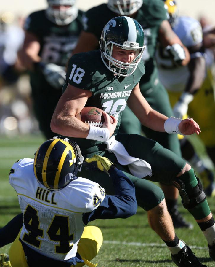Michigan State's Connor Cook is tackled by Michigan's Delano Hill during first quarter action on Saturday, Oct. 25,2014 at Spartan Stadium in East Lansing, Mich. Michigan State won 35-11. (Kirthmon F. Dozier/Detroit Free Press/MCT)