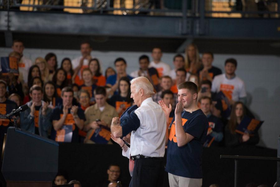 Vice President Joe Biden puts on an its On Us shirt at Campus Recreation Center East on Thursday as Illinois Student Senate Vice President-External Matt Hill claps. 