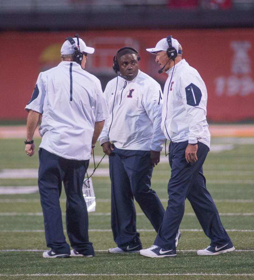 Illinois coaches Mike Ward (left), Tim Banks (center) and Bill Cubit converse on the field during Saturdays game against Nebraska at Memorial Stadium. Illinois won 14-13.