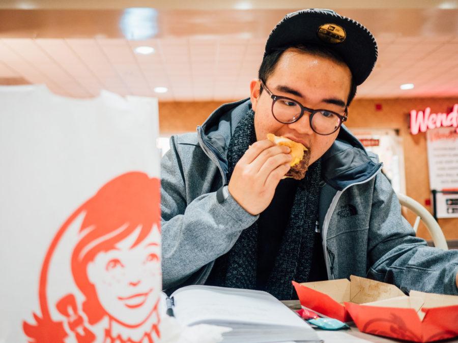 Yuli Wang, student in LAS, eats a Wendys cheeseburger at the food court in the Union on Wednesday.