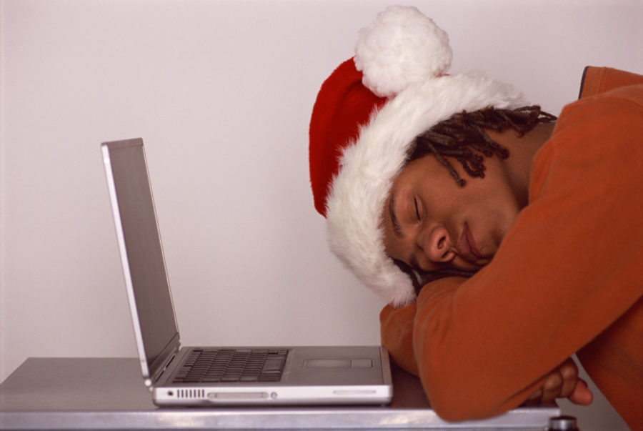 Man wearing Santa hat sleeping in front of laptop computer