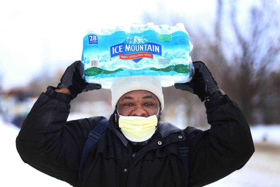 Carl Huntere, 48, of Flint, Mich., walks home through the snow from the North End Soup Kitchen in Flint on Wednesday, Jan. 13, 2016, where he received a case of free bottled water. (Regina H. Boone/Detroit Free Press/TNS)