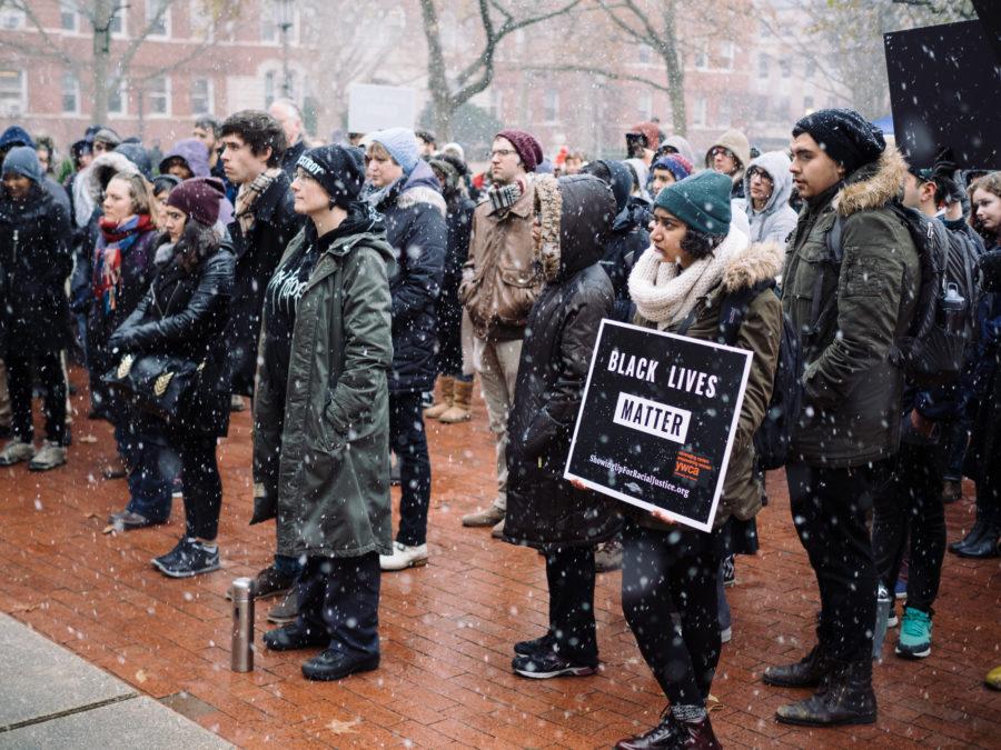 Students hold signs in protest while listening to Love Note in snow at the Anniversary Plaza on Wednesday, Dec 2 2015.