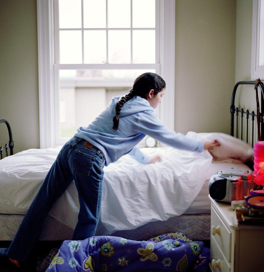 Girl (10-12) making bed, rear view