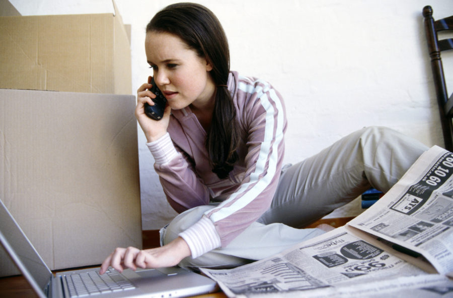 Woman multitasking with cell phone, laptop and newspaper