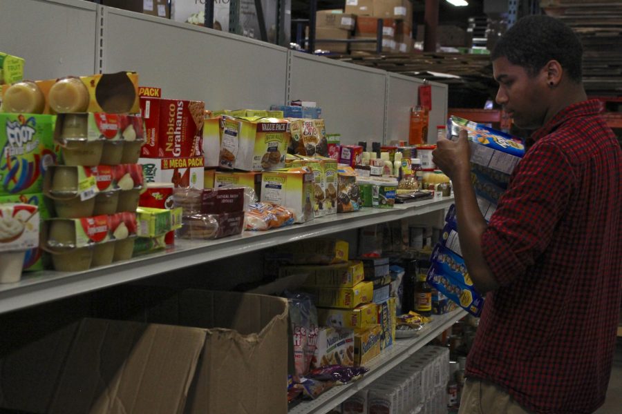 Xavier Gourdine, a freshman in Computer Science, stocks food while volunteering at the Eastern Illinois Foodbank in Urbana on Tuesday afternoon. 