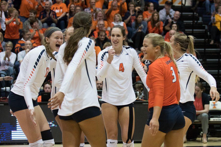 Players (Michelle Strizak (4)) on the Womens Volleyball team cheer and congratulate each other after scoring a point.