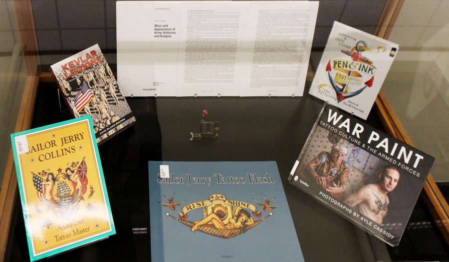 Artifacts for the Symbols of Service exhibit sit in one of six display cases on the first floor of the Main Library. The gallery focuses on U.S. veterans and their tattoos, while also addressing other topics such as readjusting to civilian life after military service.