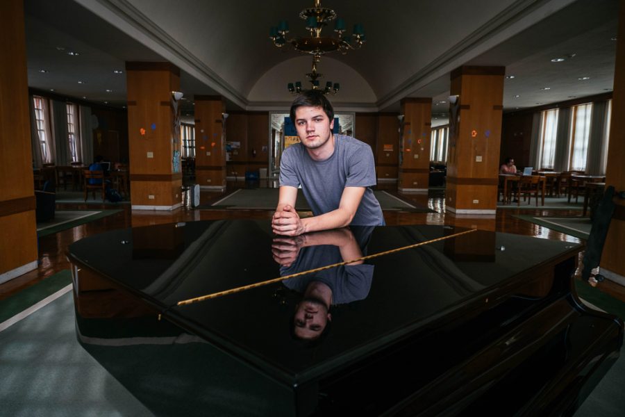 Tad Arndt, freshman in LAS, rests on the grand piano in Lincoln Avenue Residence Hall. Arndt writes his own music and uses his compositions as a force of social change.