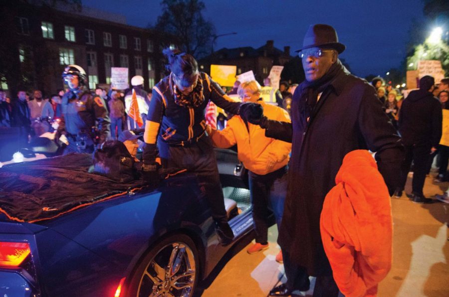 Chancellor Robert Jones helps Dr. Lynn Hassan Jones exit their car due to the 2017 Homecoming Parade being blocked by an anti-Chief Illiniwek protest on Friday. Earlier this week, following a meeting with alumni, students with indigenous backgrounds and Native American House staff, Illinois Student Government sent out information that it would be boycotting the parade.