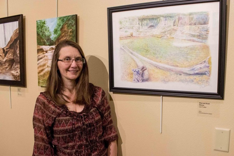 Lori Fuller poses in front of her artwork showcased in Presby Halls  Artists Alley. Fuller enjoys creating art that reflects the world around her.  