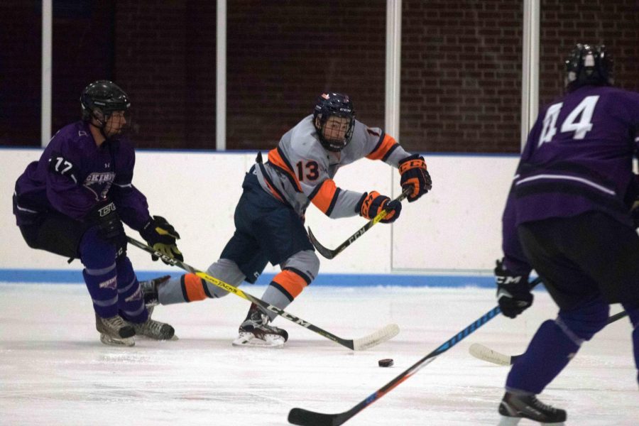 James McGing (13) passes the puck past McKendrees players to his line mate across the ice at the Ice Arena on Friday, Oct. 13th. Illinois beat McKendree 4-2.