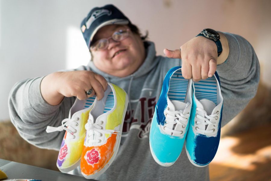A Creative Souls employee holds up shoes they painted. The local shoe company, which specializes in hiring people with disabilites, is attempting to raise $50,000 to expand hiring.