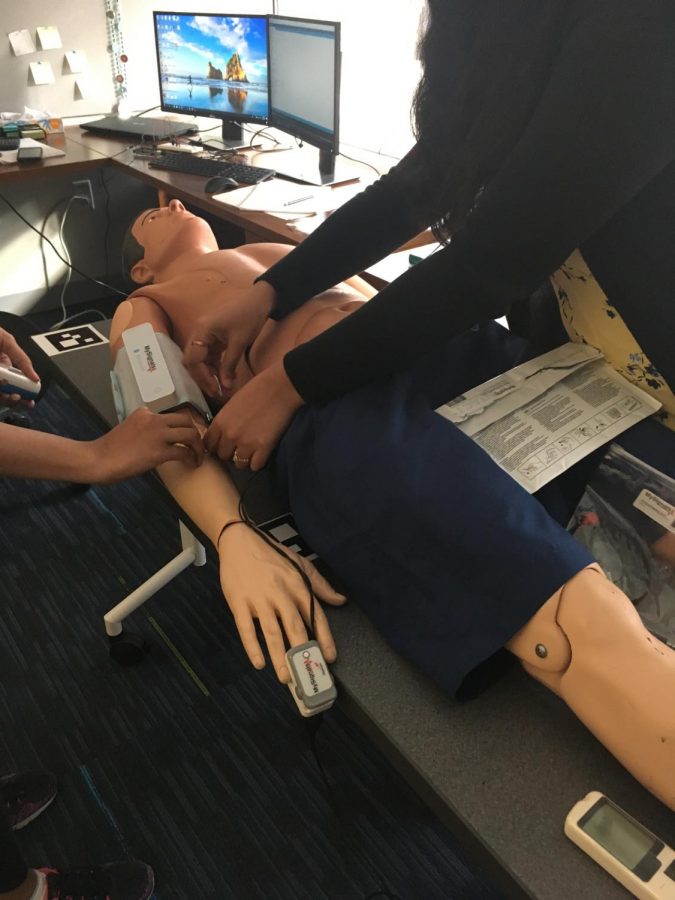 Lab engineers in the Health Care Engineering Systems Center demonstrate sensors that measure patients’ vitals (blood sugar, heart rate, etc) and connect ongoing data to an iCloud system that can be shared with the patients’ doctor on a dummy/mannequin.