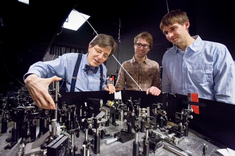 Physics Professor Paul Kwiat (left) working with graduate students in the lab at Loomis Laboratory of Physics. Kwiat is working on improving quantum computing. 