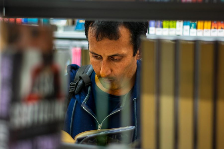 Hezbullah Akmal skims fiction novels at the Champaign Public Library on Monday. Akmal, an immigrant from Afghanistan, came to Champaign-Urbana last year when he was being threatened after working with the American government. 