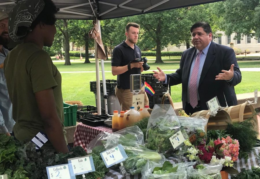 Illinois+Gov.+JB+Pritzker+outside+the+Illini+Union+on+Wednesday+talking+to+students+at+the+Sustainable+Student+Farm+stand.+Pritzker+talked+about+the+new+capital+construction+program+in+the+Illini+Union+earlier+that+day.+