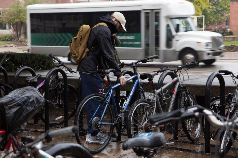 A student unlocks his bike next to Wright Street on Oct. 26. Columnist Andrew argues the existing dichotomy in the fat shaming debate is a fallacy and proposes a third cause: American culture. Bicycling is a great way to offset the sedentary lifestyle.