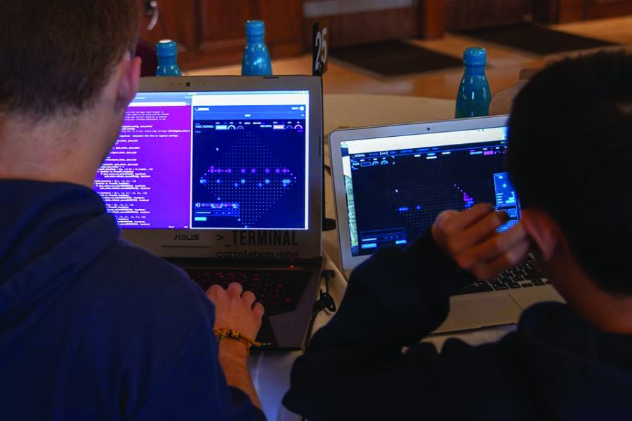 Two students create code during a competition. At Terminal Live events, a team of students write code to compete in an online strategy game against other teams.