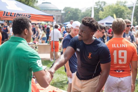 A student shakes the hand of a representative of the Illini Rugby on Quad Day Aug. 26. Participating in these events takes preparation. Consider the head, the crowds and the multitude of opportunities thrown your direction.