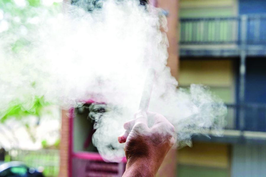 A student vapes in an apartment complex near the North Quad on Saturday. As of Aug. 26, the University is a smoke-free and tobacco-free campus.