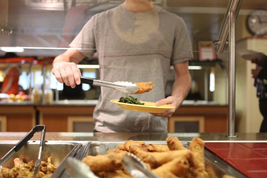 A student takes an egg roll from the Busey-Evans buffet on Friday. The Busey-Evans dining hall will be closed next year.