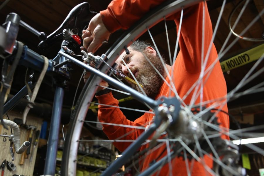 Jacob Benjamin, manager at the Campus Bike Center located on Pennsylvania Avenue, repairs a bike on Friday. The staff of the bike shop, Benjamin included, teaches people how to perform bike maintenance, like flat tires. 