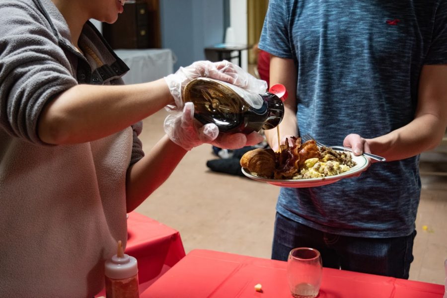 A student volunteer pours syrup on a persons plate at the University Place Christian Church on the evening of February 19, 2020.
