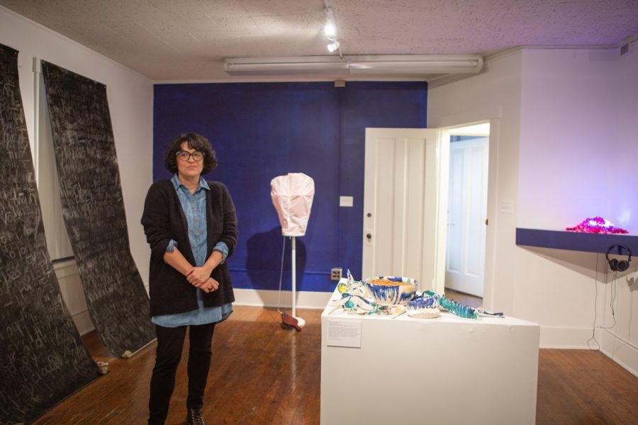 Sandra Ruiz stands next to student art at The Estacion Gallery at La Casa Cultura on Friday.