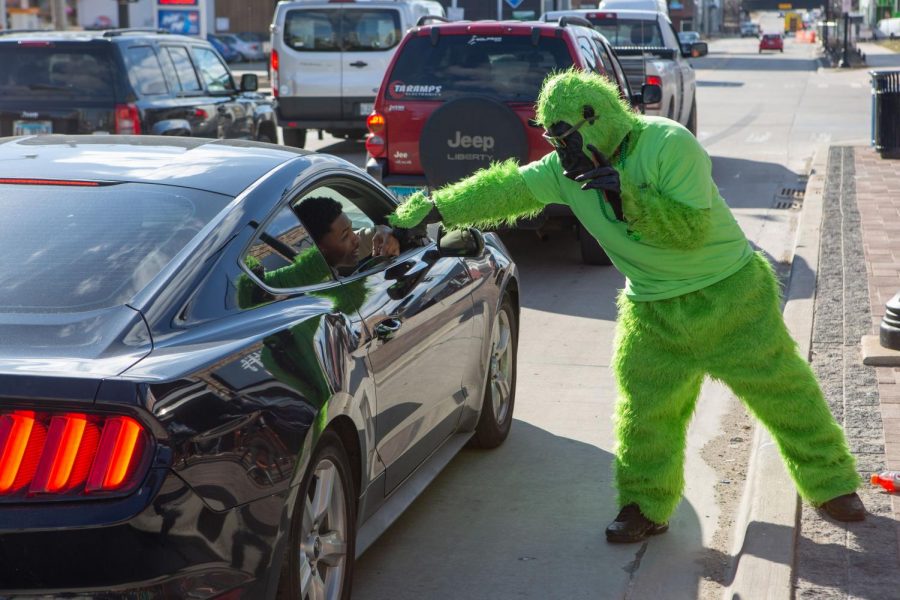 A green gorilla outside of KAM's fist bumps a passenger in a black Mustang during Unofficial on Friday.