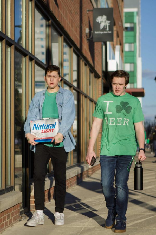 Two students stroll walk Green Street with a case of Natural Light during Unofficial on Friday.