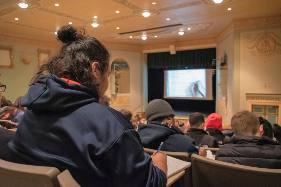 A student takes notes during his statistics lecture in Lincoln Hall Theater on Dec. 3, 2019.