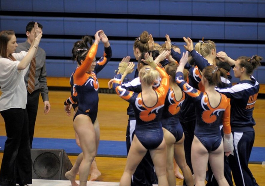 The Illinois Womens Gymnastics team celebrates after one of its members completes their routine during a match against Michigan on Feb. 7, 2014.
