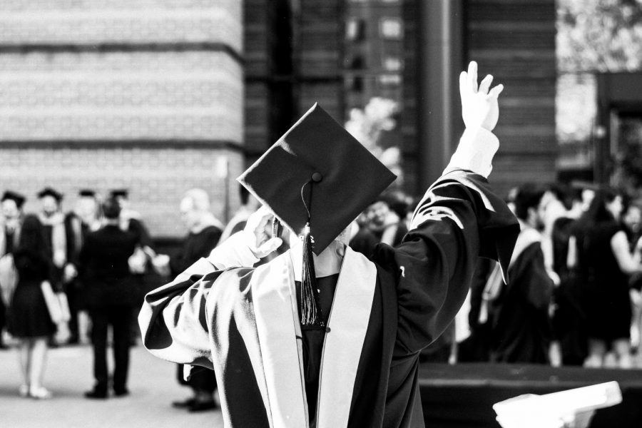 A college graduate throws a hand in the air to celebrate their most recent accomplishment.