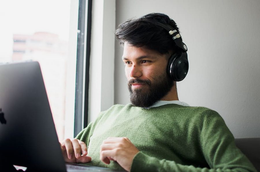 A mean wearing headphones uses his computer.