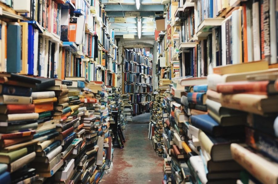 Stacks and shelves of books line the edges of a narrow corridor.