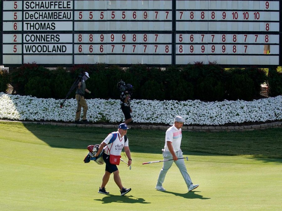 PGA Tour golfer Bryson DeChambeau (right) walks up the 18th fairway past the leaderboard showing him at 10-under during the second round of the Charles Schwab Challenge at the Colonial Country Club in Fort Worth, Friday, June 12, 2020. He finished the day tied for second with Jordan Spieth at 10-under. The Challenge is the first tour event since the COVID-19 pandemic began.