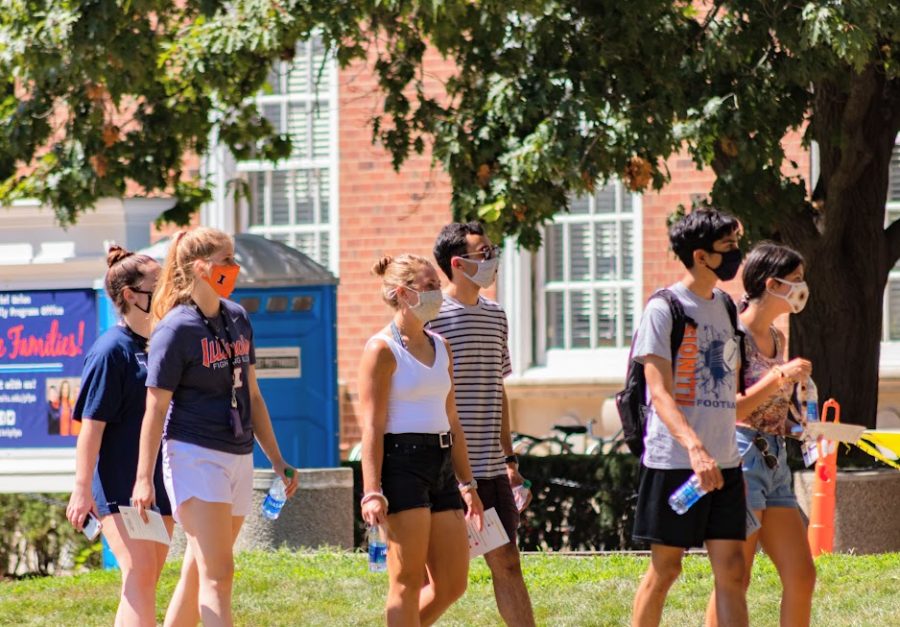 A group of students wearing masks walks through the Main Quad on Friday. Tuesday marked Champaign County’s largest single-day increase in COVID-19 cases.