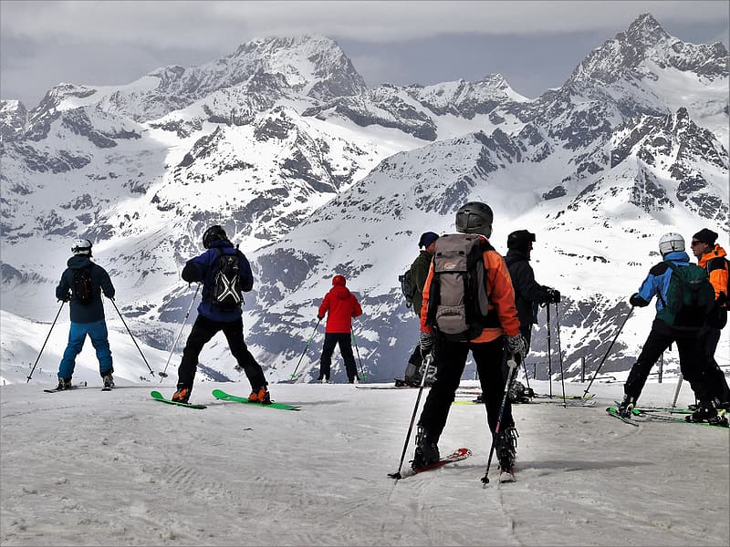 A group of skiers pause on the side of a mountain.